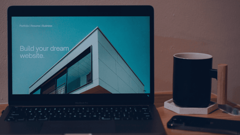 Laptop on a desk showing a website with the headline Build your dream website